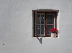 Vintage window with red flowers on white wall