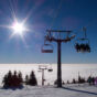 A chair lift at the top of a mountain on a sunny day